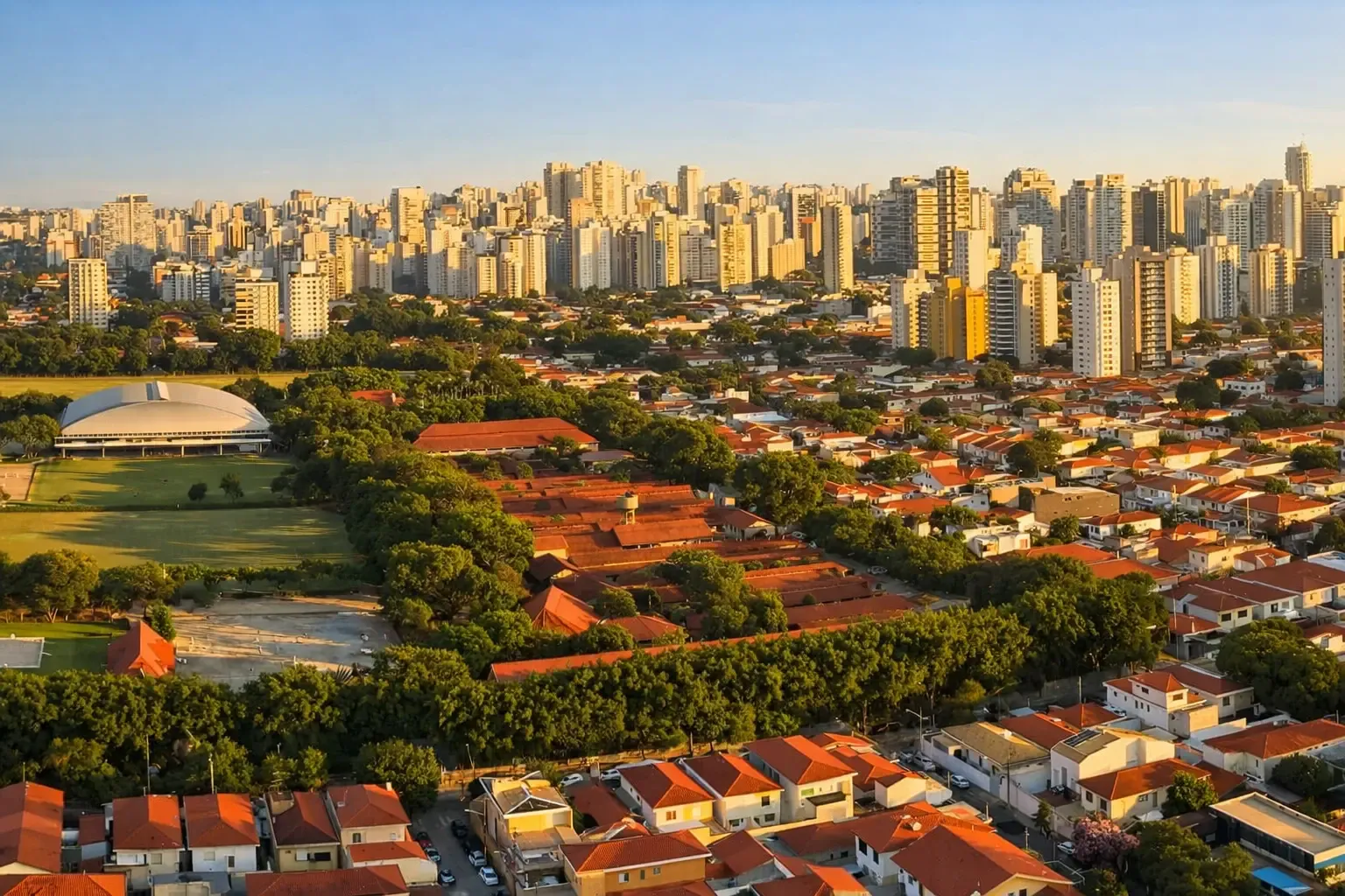 Aerial view of Brooklin with red-roof houses, green tree-lined blocks, and dense high-rise buildings in the background
