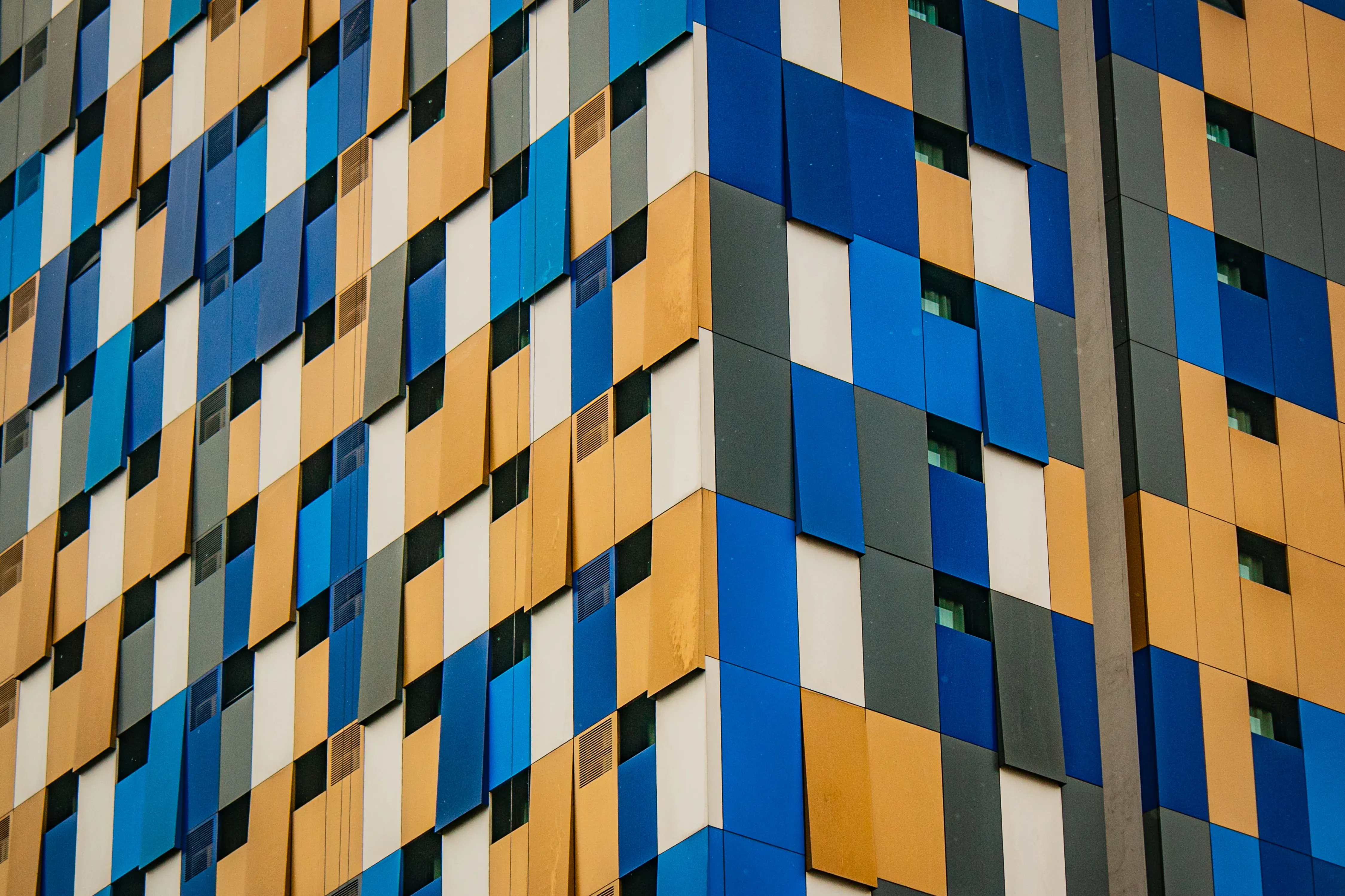 Close-up of a building facade with blue, yellow, white, and gray geometric panels