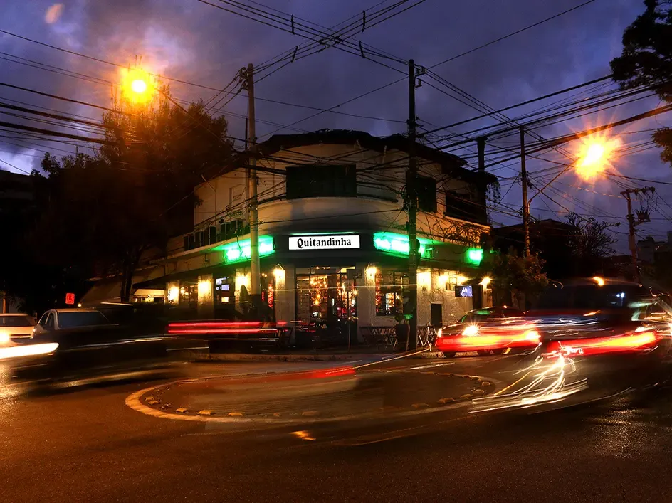 Nighttime corner bar with light trails from passing cars under overhead wires