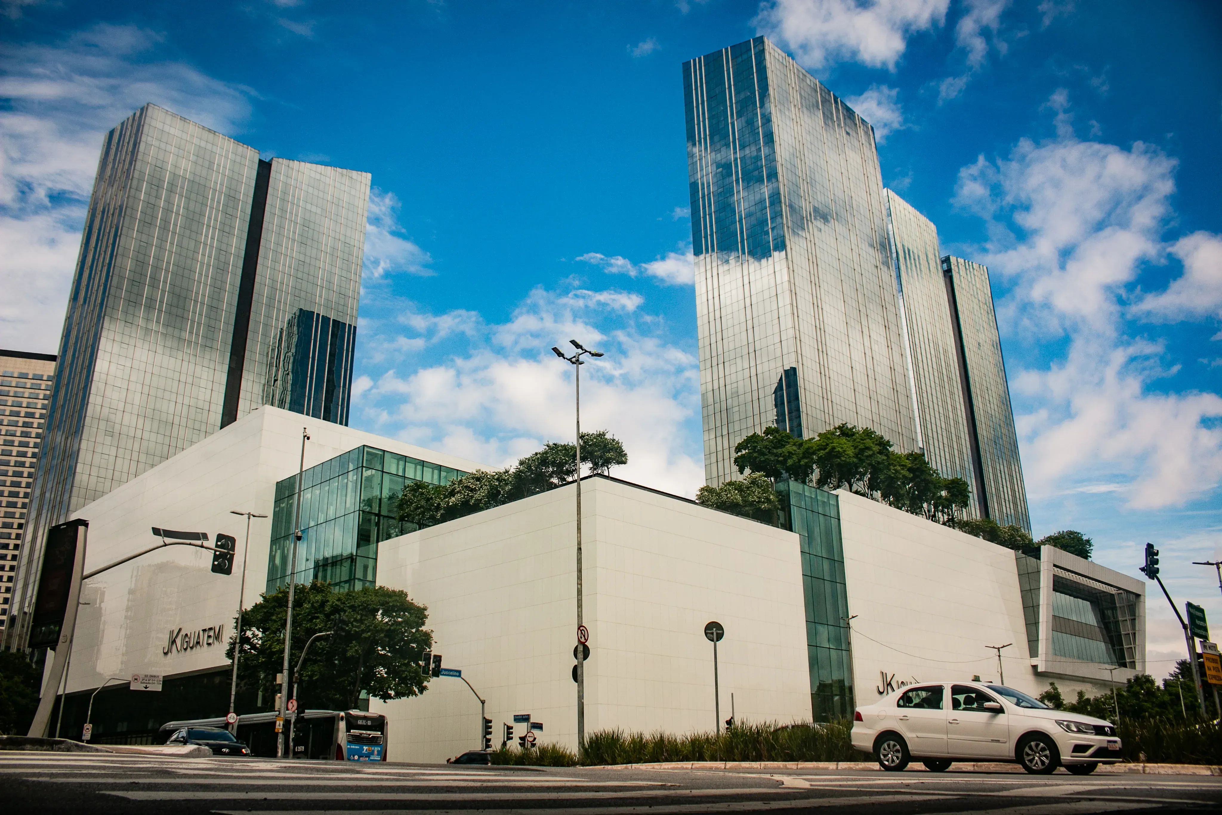 White modern complex with reflective high-rise towers under a bright blue sky