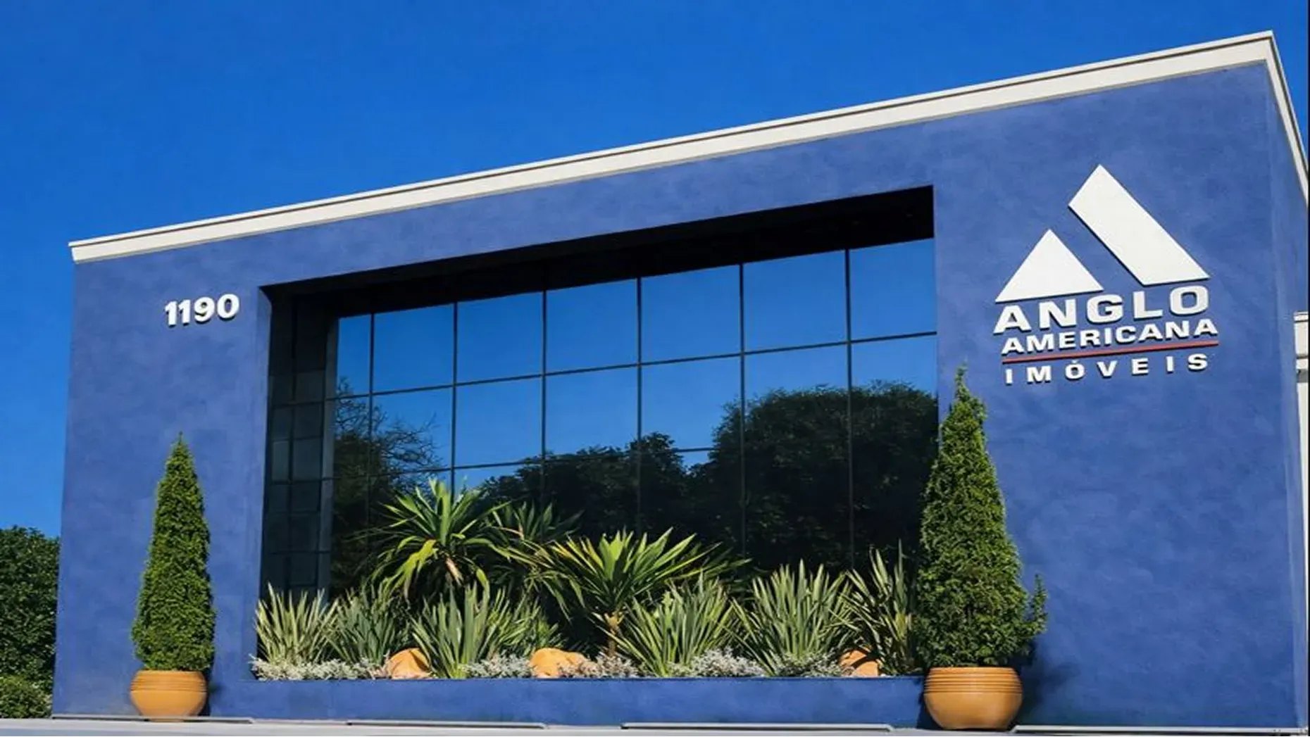 Anglo Americana office facade with blue exterior walls, reflective windows, and landscaped plants