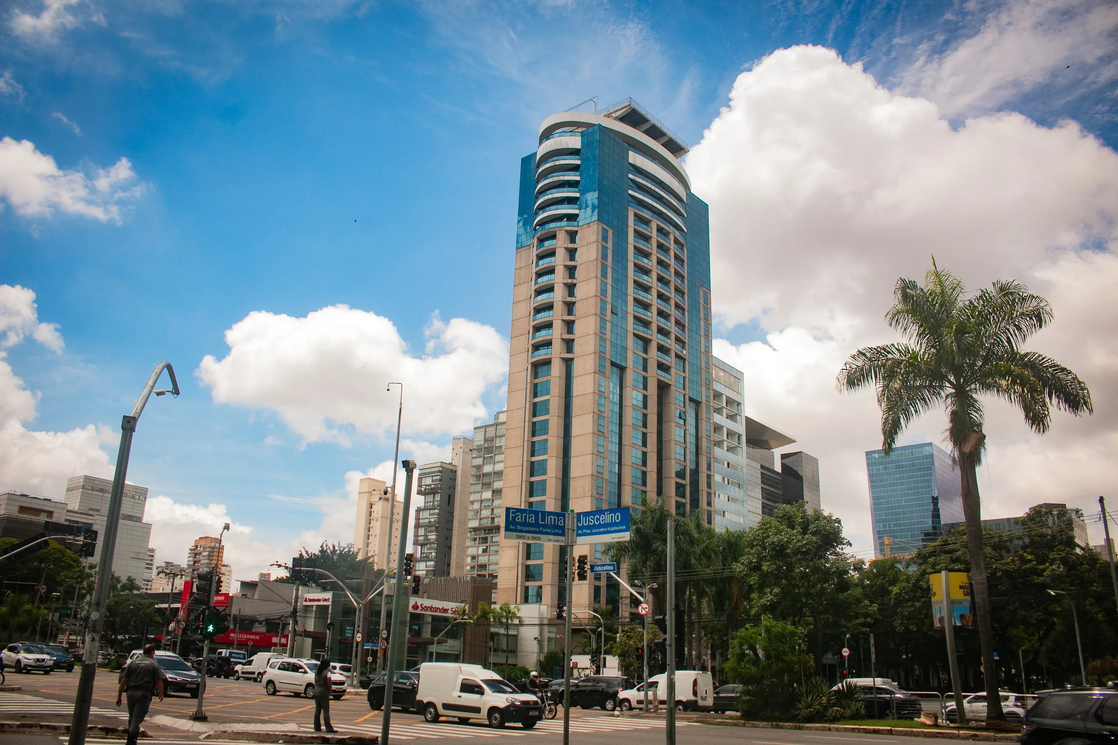 Busy avenue at Faria Lima and Juscelino with cars, palms, and a modern tower