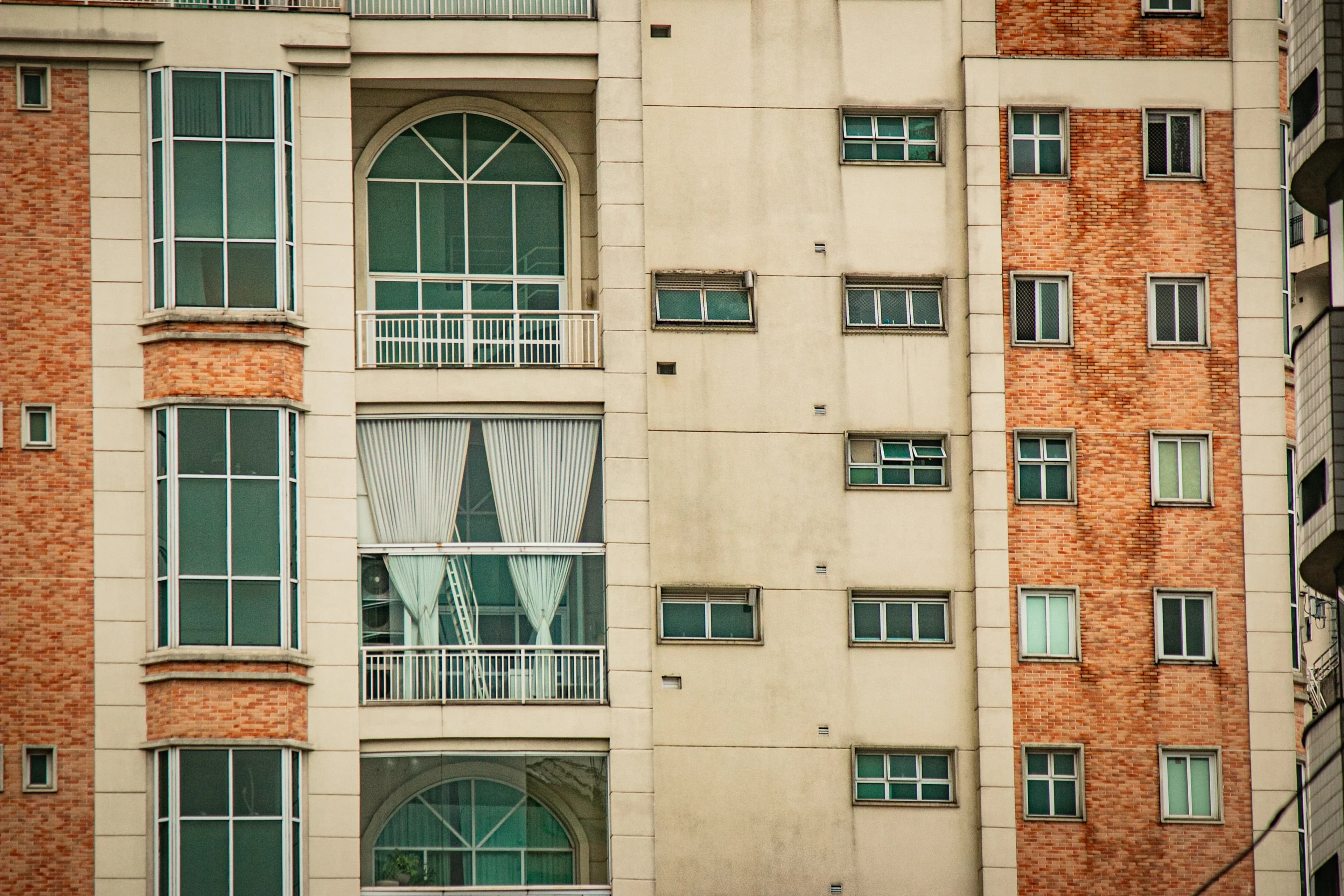 Close-up of an apartment facade with large windows and brick sections