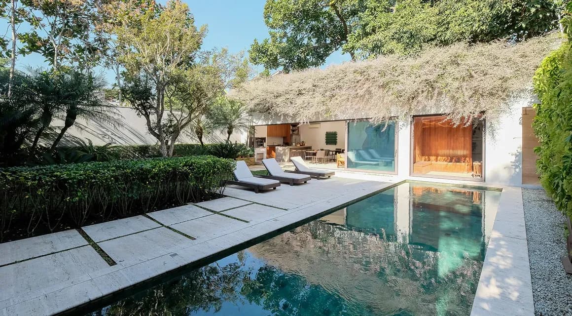 Modern pool with lounge chairs and house surrounded by trees