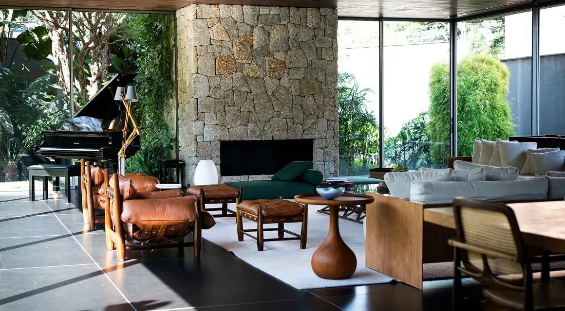 Sunlit modern living room with a stone fireplace, leather lounge chairs and a grand piano