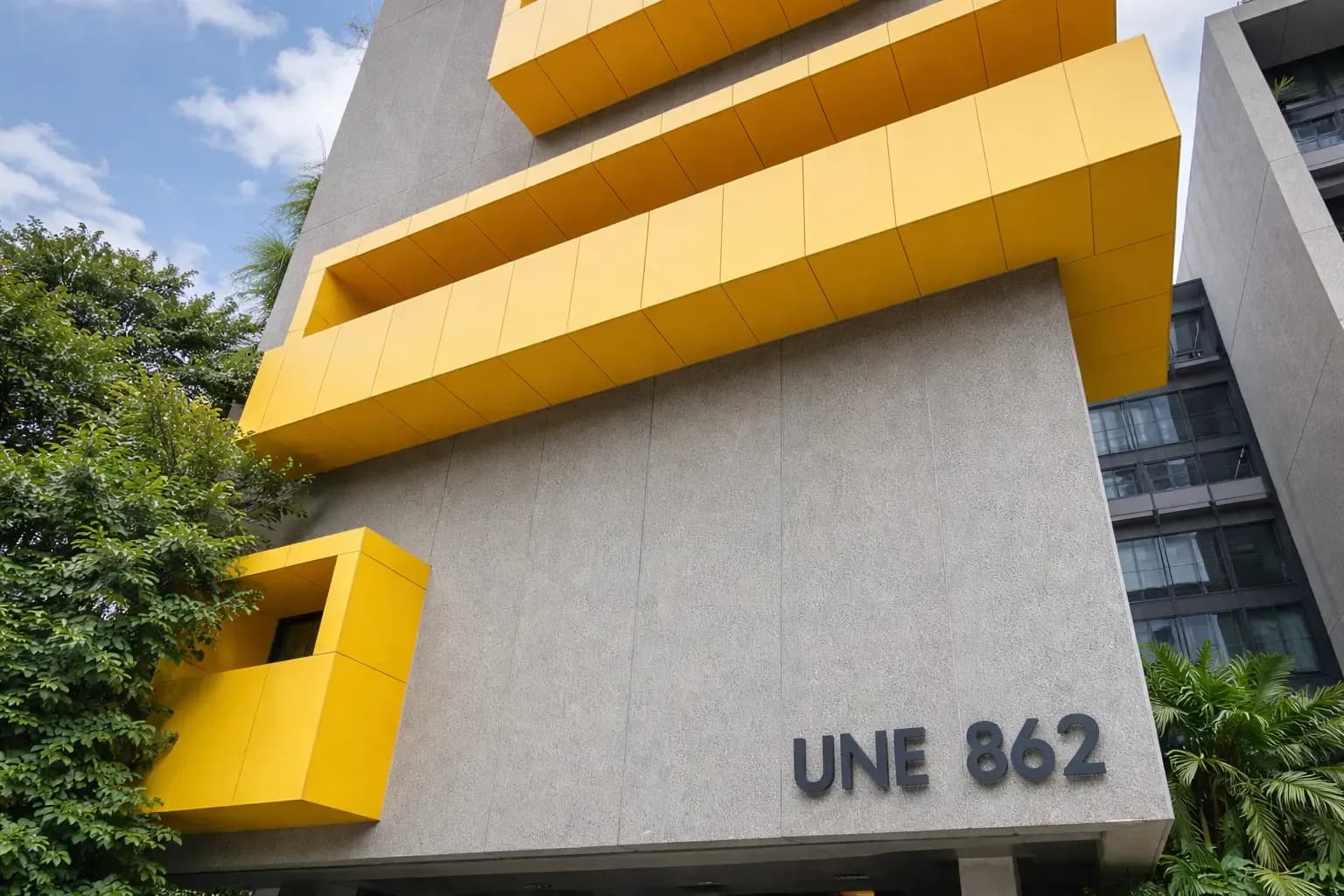 Modern building facade with bold yellow balconies and the sign “UNE 862.”