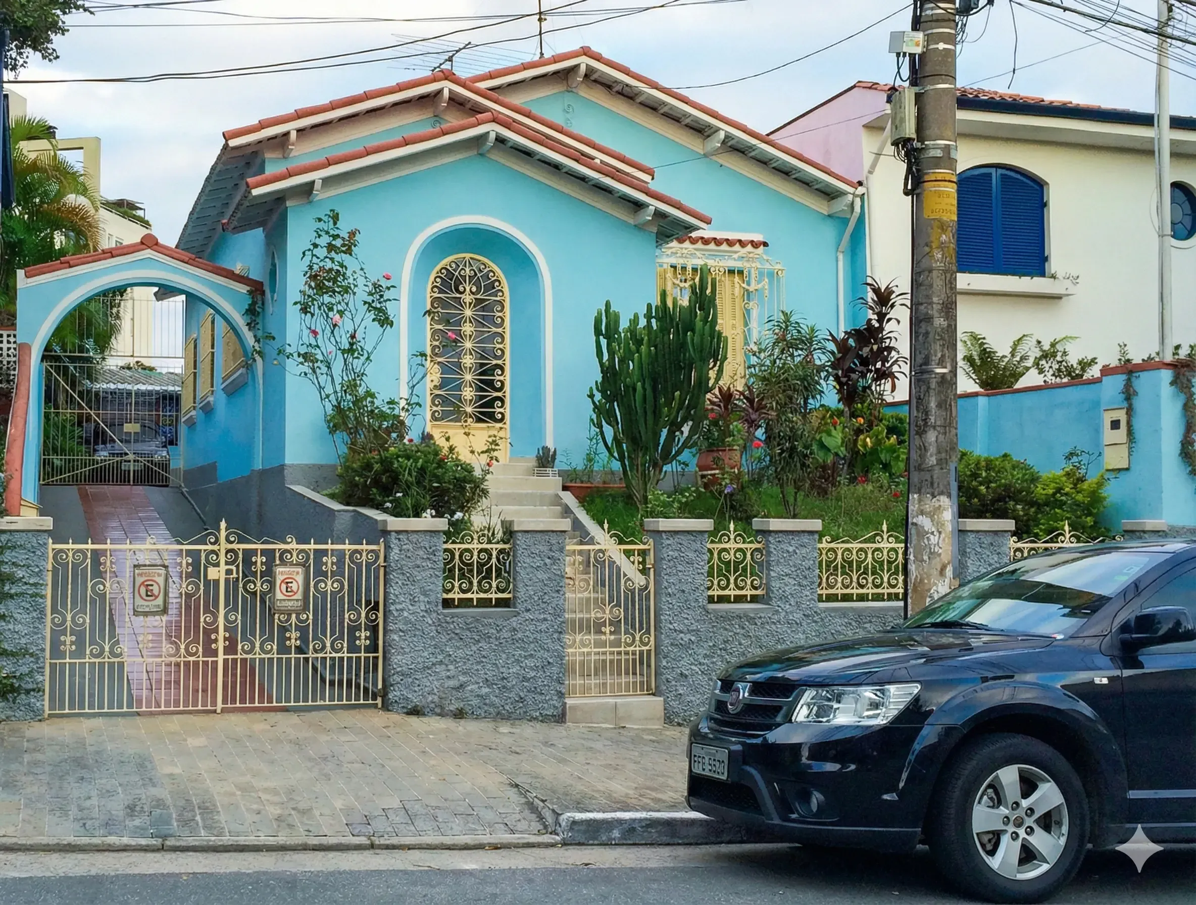 Bright blue house with decorative gate, front garden, and parked car nearby